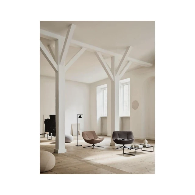 Interior design with two modern swivel armchairs, black coffee table, and floor lamp in a bright, minimalist setting with wood floors.