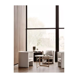 Modern interior scene featuring cream upholstered armchairs and a wooden coffee table in front of a large window.