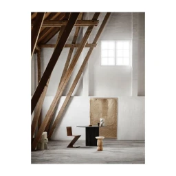 Interior shot featuring a wooden dining table, a geometric chair, and a woven tapestry in a room with exposed beams.