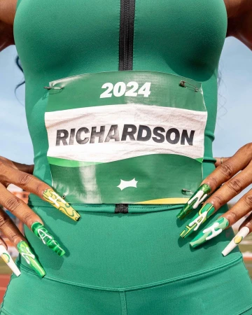 Close-up of an athlete in a green uniform with a racing bib that reads 'Richardson' and '2024,' showcasing her manicured nails.
