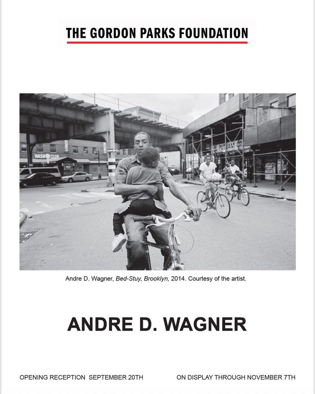 Black and white photograph captures a man on a bicycle holding a child, with other cyclists and urban Brooklyn street scene visible.
