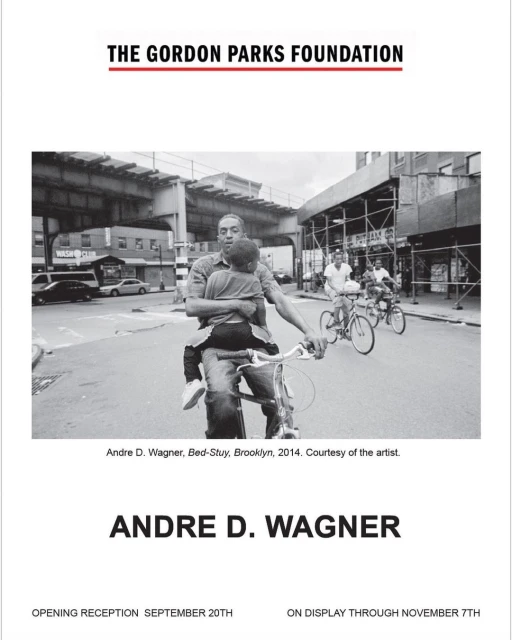 Black and white photograph captures a man on a bicycle holding a child, with other cyclists and urban Brooklyn street scene visible.