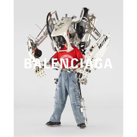 Person wearing a red t-shirt and denim pants with a white and silver mechanical exoskeleton suit against a white background. 
