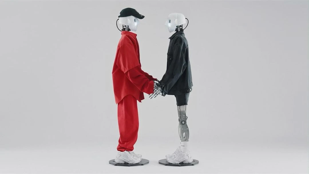 Two robots, one in red and one in black, are standing next to each other and holding hands in a neutral, indoor setting with a white background.