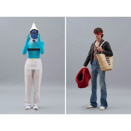 Two models pose in a photo studio against a grey backdrop: one in Smurf-like blue body paint and one in 70s-inspired fashion.