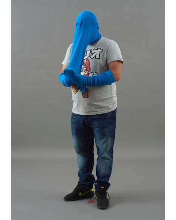 Full-length studio shot of a man wearing denim jeans, black sneakers, and a gray t-shirt with a character graphic, covered in a blue fabric.