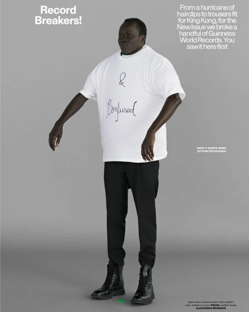 A tall, dark-skinned man stands centered in a full shot, wearing a white '& Confused' t-shirt, black pants, and boots against a neutral backdrop.
