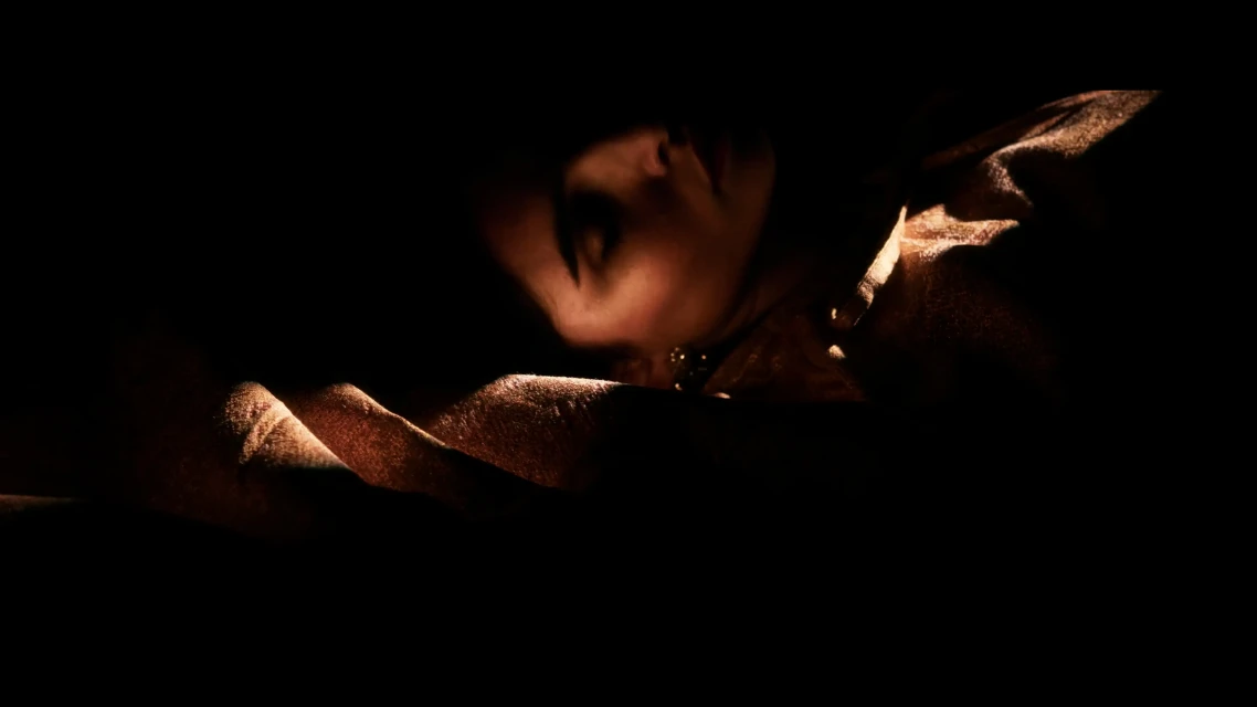 Close-up portrait of a woman in dramatic lighting, with a focus on her face and body, creating a sensual and intimate scene.