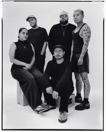 Group portrait of five people in an indoor setting, showcasing a diverse group in a casual yet stylish composition with a white backdrop.