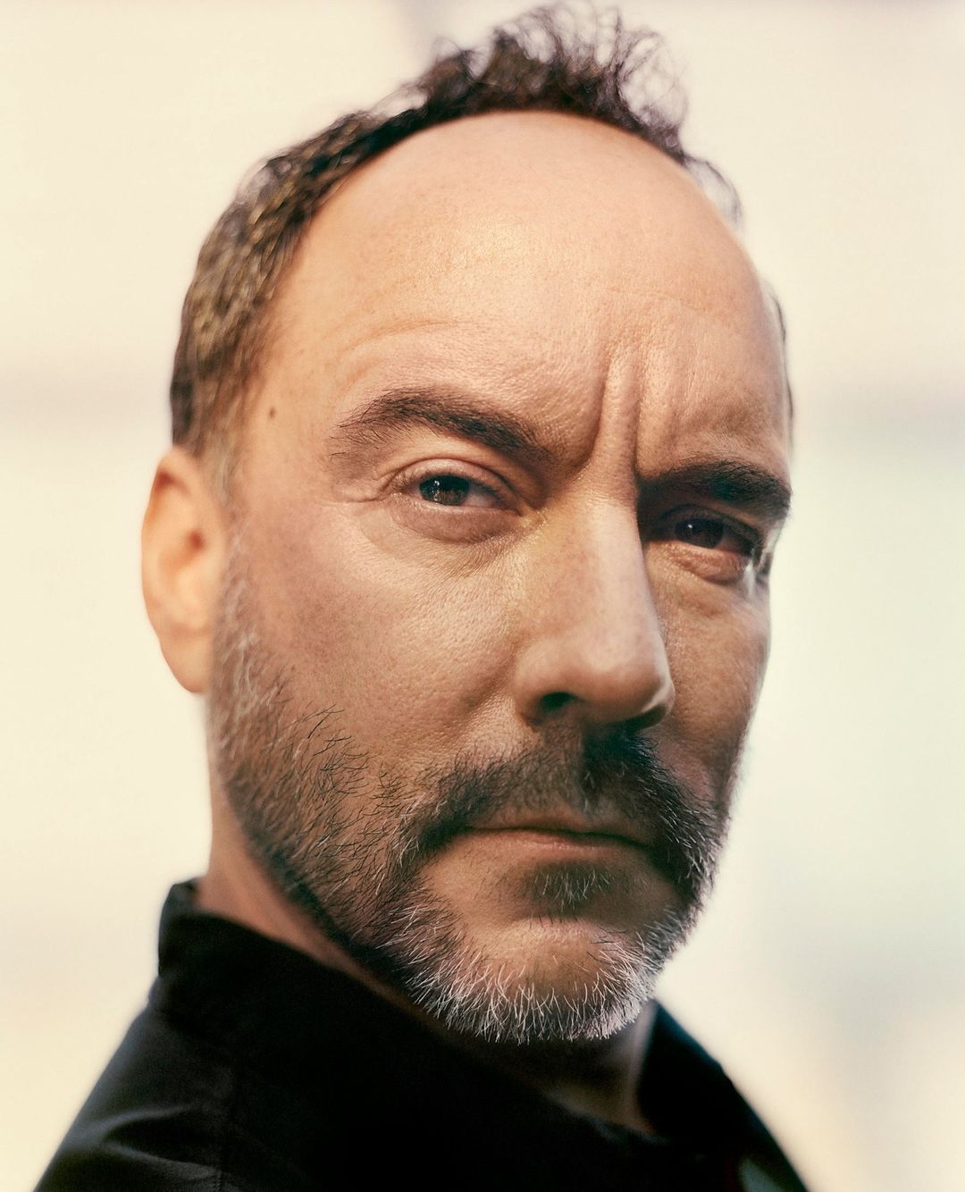 Close-up portrait of a middle-aged man with short thinning hair, a trimmed grey beard, and a serious expression.