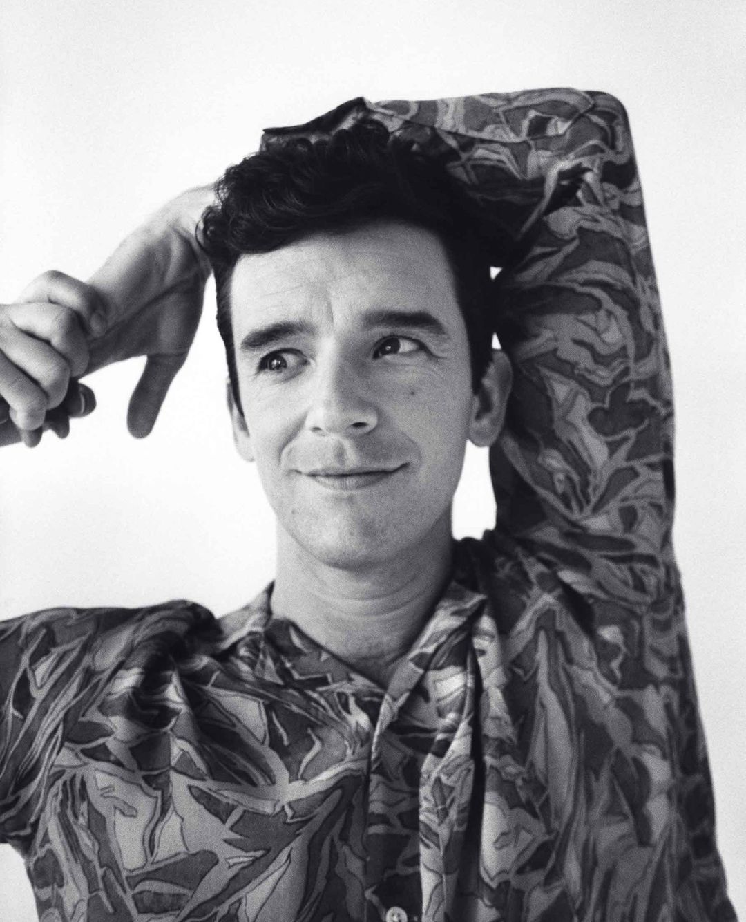 Portrait of a man in a patterned shirt with hands behind his head by photographer Andreas Laszlo Konrath.