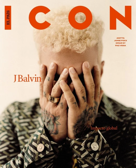 Magazine cover featuring J Balvin with hands covering his face, wearing a patterned jacket, against a light beige background. Orange ICON logo.