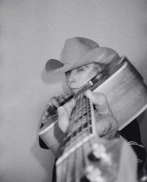 Man wearing a cowboy hat holding an acoustic guitar facing the camera by Andreas Laszlo Konrath