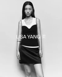 Monochrome fashion portrait of a model wearing a layered black and white top and a dark skirt against a plain background
