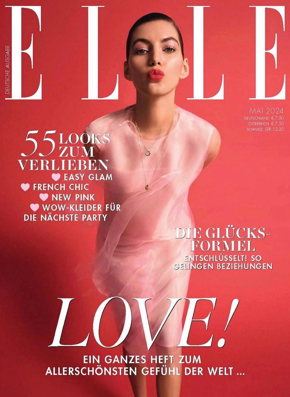Elle magazine cover featuring a female model wearing a sheer pink top, posing with pursed lips, on a solid pink background.
