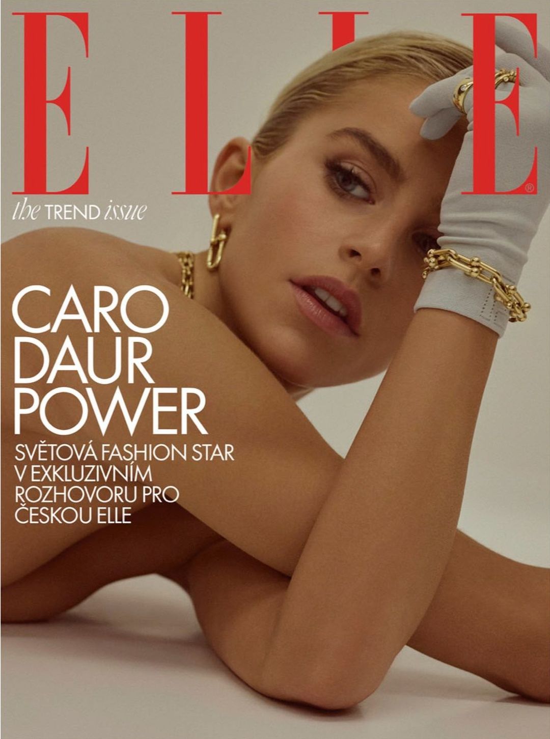 Elle magazine cover featuring model Caro Daur wearing white gloves and gold jewelry in a close-up portrait with a neutral background.