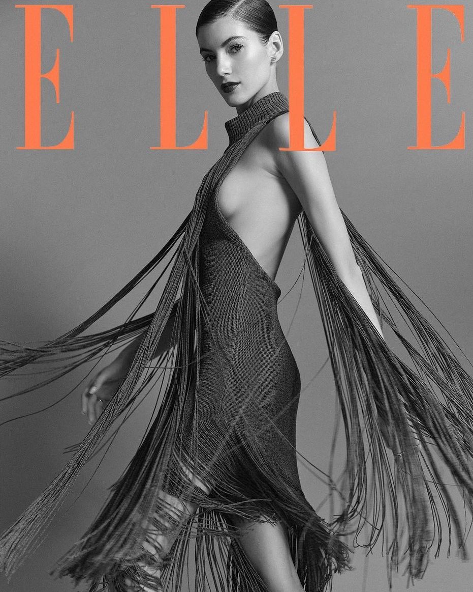 Elle magazine cover featuring a woman wearing a dress with fringe, set against a grey backdrop with orange 'Elle' lettering.