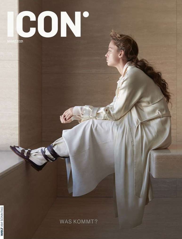 Magazine cover featuring a young woman in a cream outfit, seated and looking away from the camera in a minimalist interior setting.