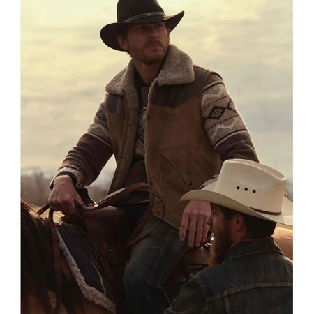 Two men on horseback, one wearing a black cowboy hat and a sheepskin vest, the other a white cowboy hat, in an outdoor setting.