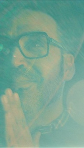 Portrait of an adult man with a beard wearing glasses, featuring creative lighting and a soft, dreamy teal color palette.