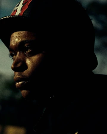 Close-up portrait of a Black man wearing a baseball cap in low-key lighting by photographer Andree Ljutica.