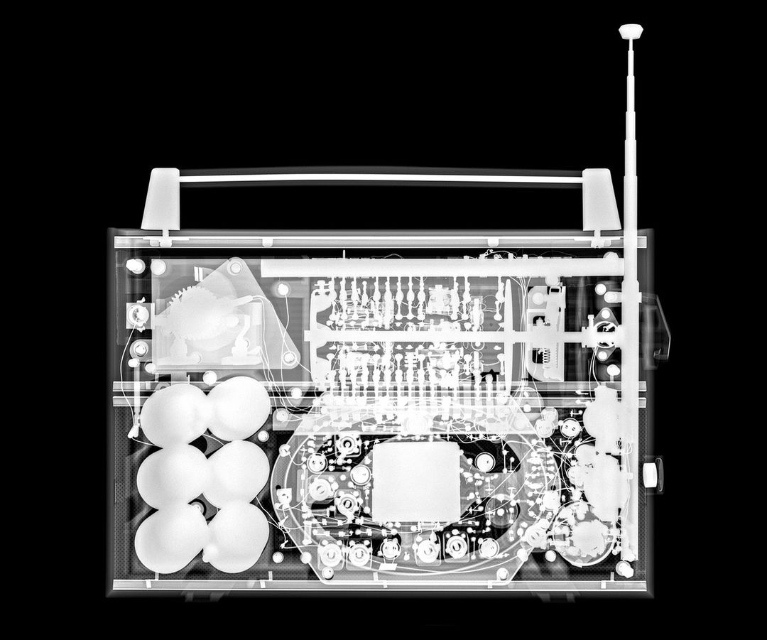 X-ray view of a vintage radio revealing internal components, electronics, and wiring, set against a black background for contrast.