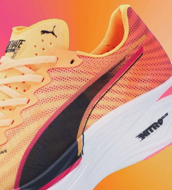 Close-up of a Puma running shoe in shades of orange, yellow, black, and white, showcasing its design and construction details.