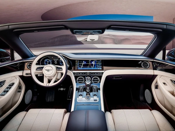 Interior view of a luxury convertible featuring a beige leather interior, digital displays, and a view of the car's exterior.