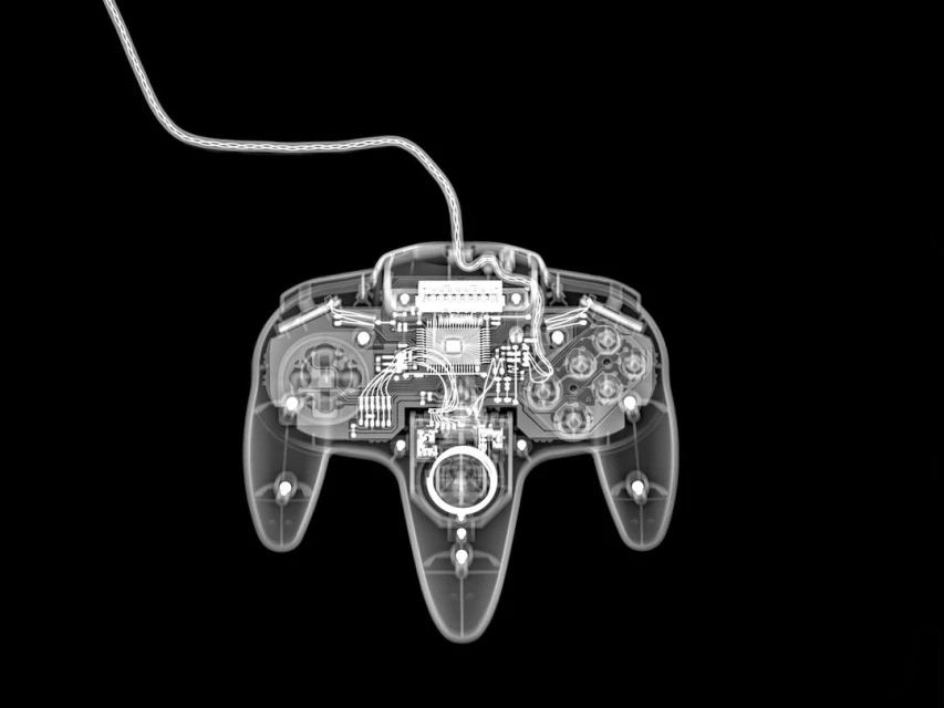 X-ray image of a vintage N64 game controller with a cable, displaying its inner mechanisms against a dark backdrop.