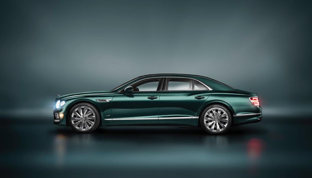 A sleek, dark green Bentley sedan is showcased in a studio shot, emphasizing its luxurious design and elegant lines, against a muted backdrop.