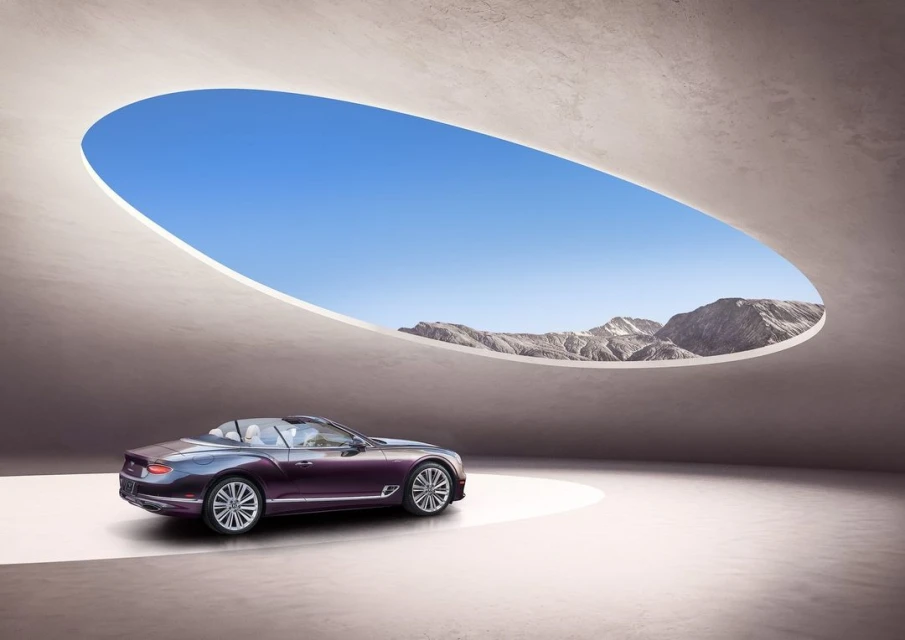 Luxury purple Bentley convertible car in a modern studio with a view of distant mountains. Automotive beauty shot.
