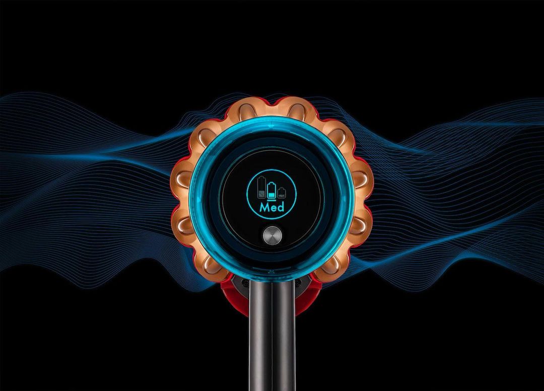 Close-up of a Dyson vacuum cleaner with a digital display showing the medium setting, set against a black background with blue waves.