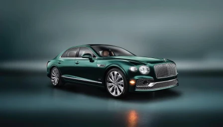 Dark green luxury sedan car parked in a moody studio setting with dramatic lighting on a polished floor.