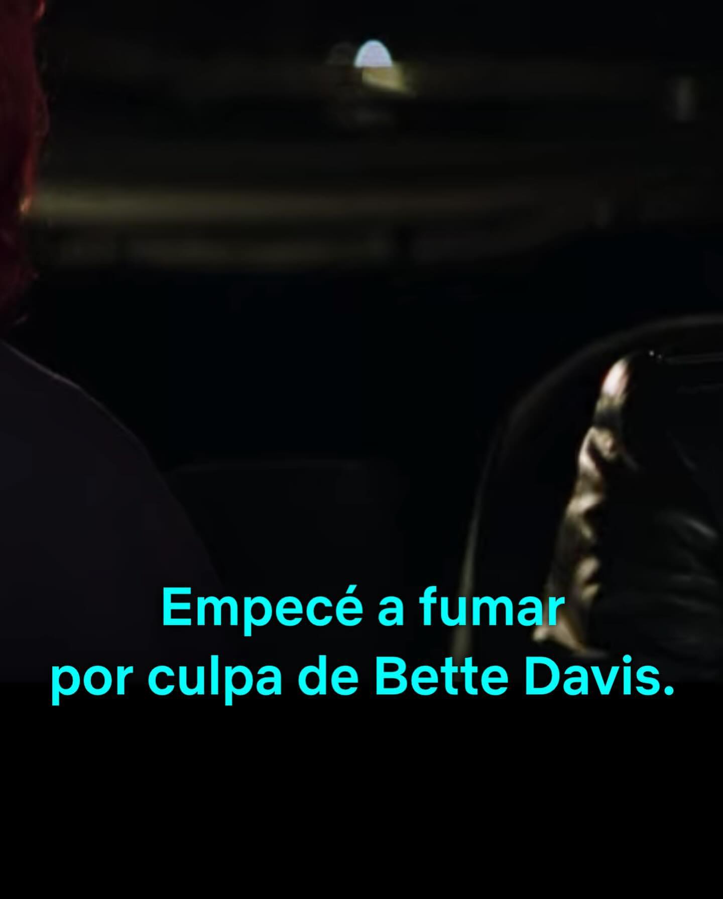 Partial view of two people at night with dark lighting, one person faces away, and text overlay says, 'I started smoking because of Bette Davis'.
