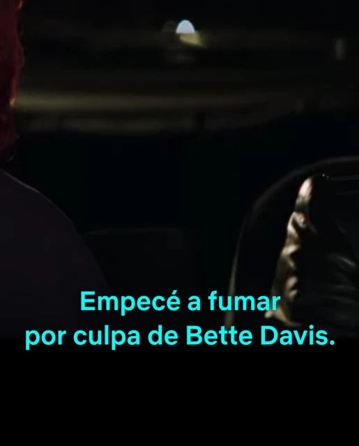 Partial view of two people at night with dark lighting, one person faces away, and text overlay says, 'I started smoking because of Bette Davis'.