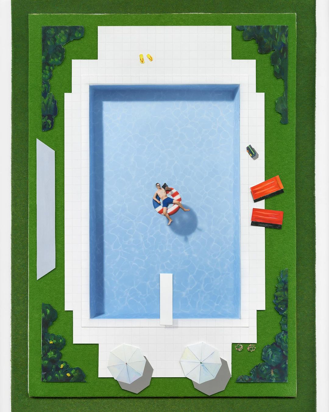 Aerial view of a couple floating on an inflatable in a swimming pool surrounded by green grass and white umbrellas on a sunny day.