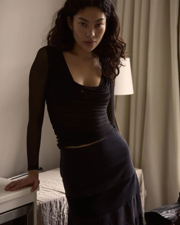 Portrait of an Asian woman in a black top and skirt posing indoors with soft natural light by photographer Andrew Day.