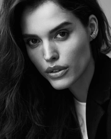 Close-up monochrome portrait of a woman wearing a dark blazer and hoop earring photographed by Andrew Day.