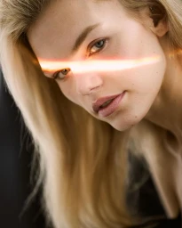 Close-up portrait of a blonde woman with a vibrant orange light flare cutting horizontally across her eyes, photographed by Andrew Day