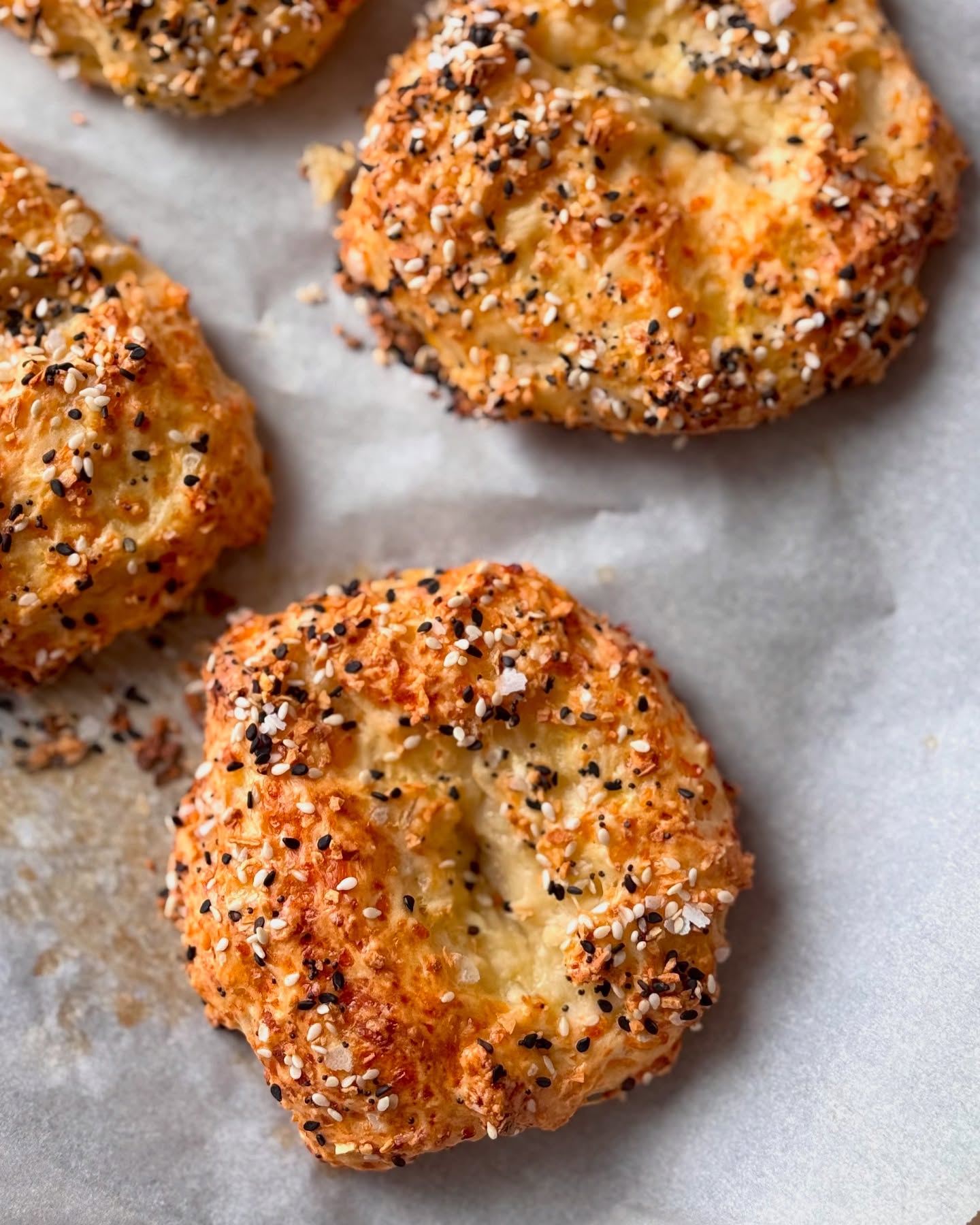 Delicious everything bagels on parchment paper, perfect for a snack or breakfast, showcasing golden-brown baked goods with tasty toppings.