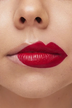 Close-up macro shot of lips wearing bold red lipstick with half the lips bare by photographer Lucy Alcorn.