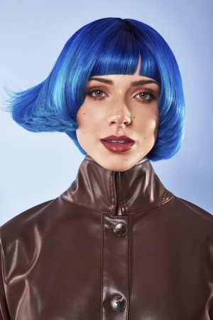 Close-up portrait of a woman with vibrant blue bob hair wearing a brown leather jacket against a light blue background.