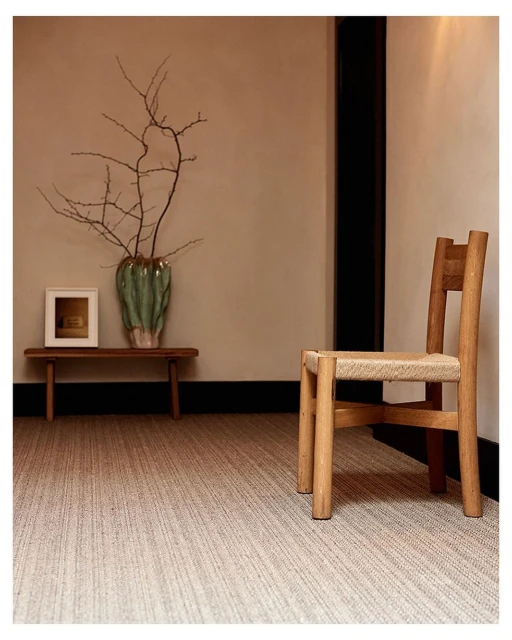 Interior scene features a light wood chair with woven seat, a bench holding a vase with branches, and beige carpet.