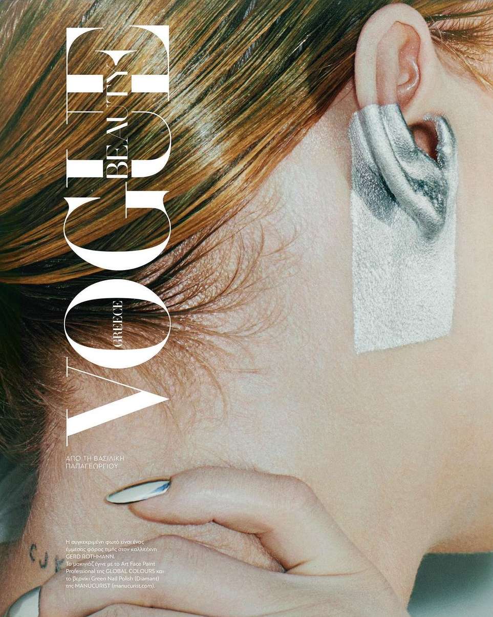 Close-up of a woman's head and hand showcasing a silver ear cuff, with golden brown hair, in a beauty editorial fashion shot.