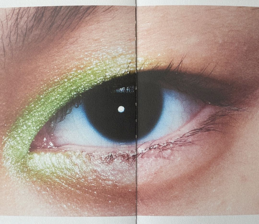 Close-up shot of a human eye with lime green eyeshadow, showcasing makeup art, beauty, and skincare in a cosmetic-focused composition.