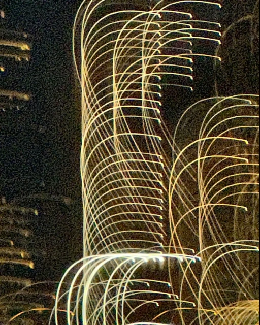 Abstract image of illuminated building at night featuring long exposure light trails creating an artistic and dynamic urban scene.