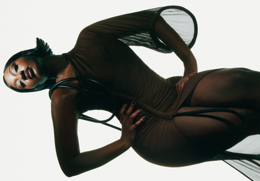 Attractive Black woman posing in sheer brown dress in studio. Fashion shot, beauty and style, sensual expression, indoor environment.