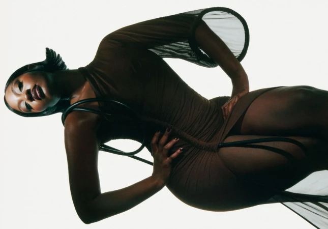 Attractive Black woman posing in sheer brown dress in studio. Fashion shot, beauty and style, sensual expression, indoor environment.