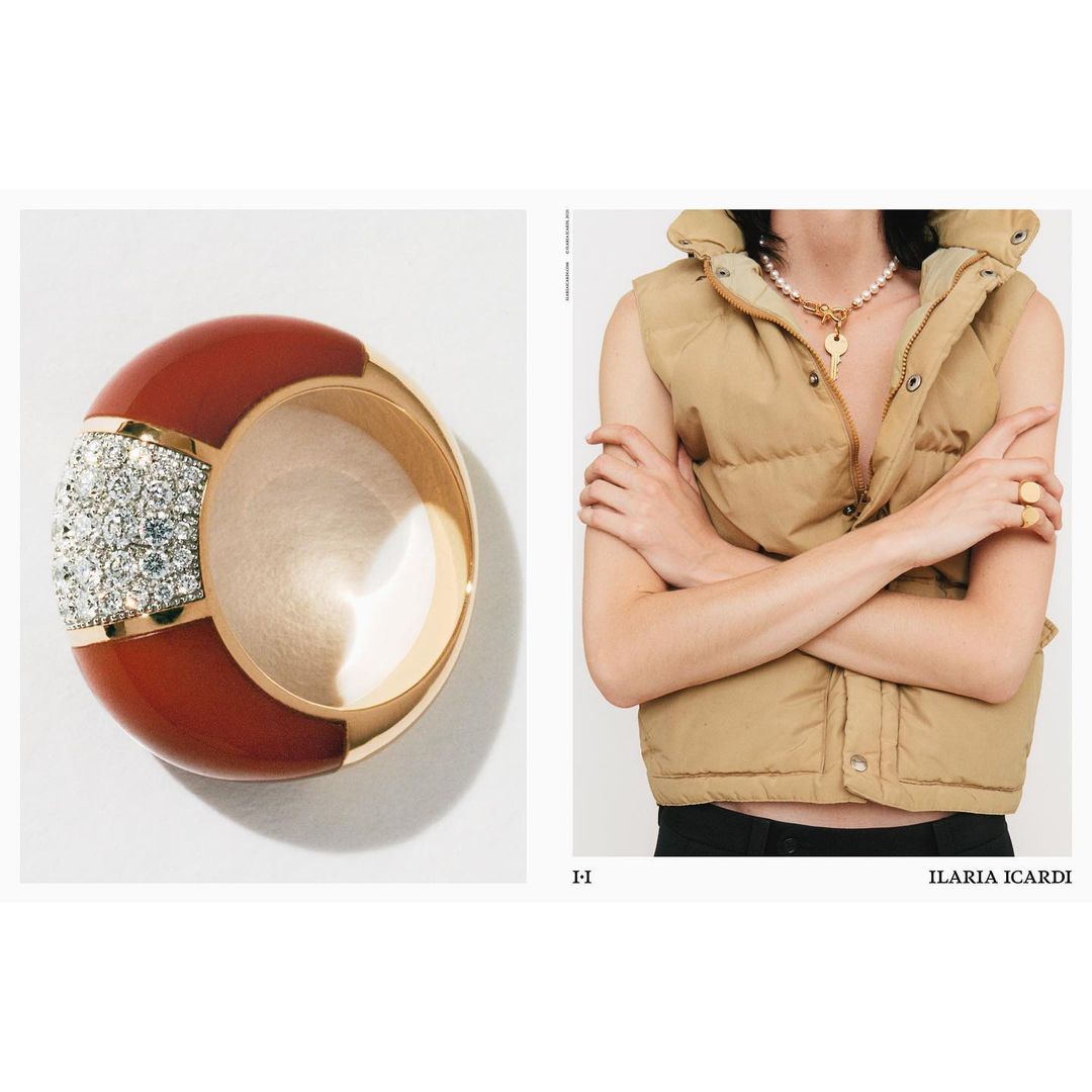 Still life shot of a red and gold ring with gemstones next to a person wearing a puffer vest and necklace with a key pendant.