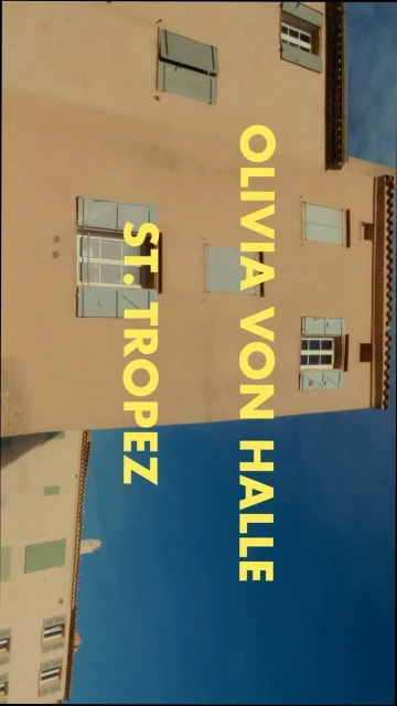Urban facade in St. Tropez, featuring residential buildings with shutters under a clear blue sky. Exterior shot showcasing architecture.